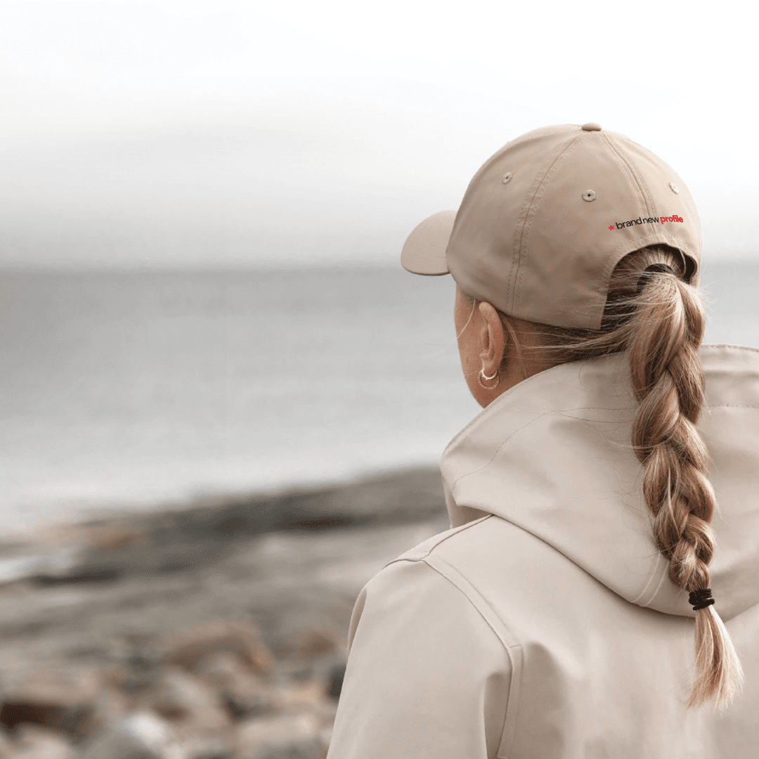 Kvinna med profilerad keps tittar ut över havet