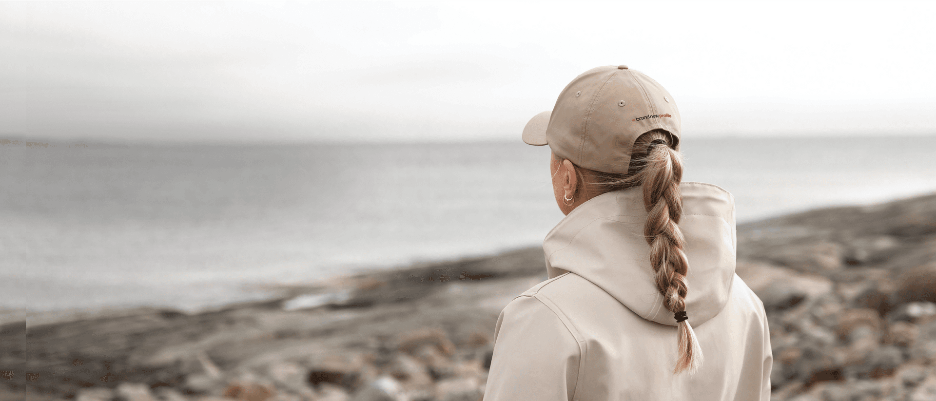 Kvinna med profilerad keps tittar ut över havet